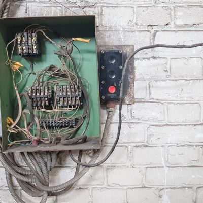 Old electrical panel on the wall of the house. Electric cables stick out from the electric panel on