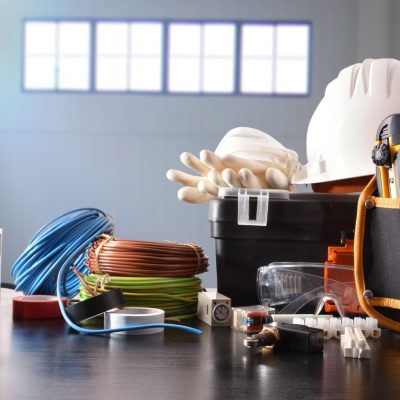 Composition with tools and electrical equipment on black table and industrial ship background. Horizontal composition. Front view.